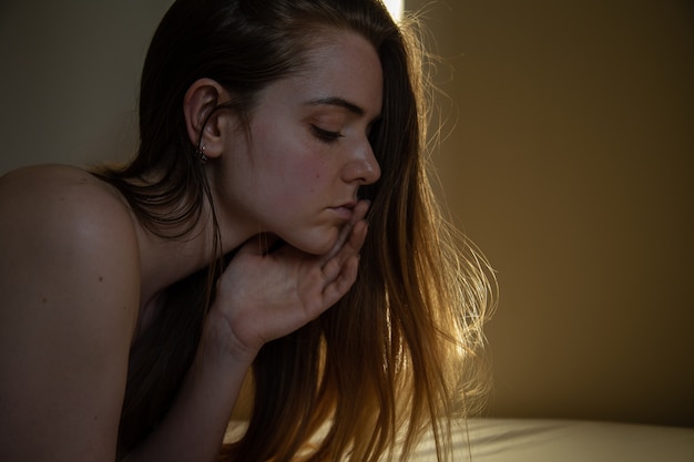 Side view portrait of young pensive sexy attractive female with close eyes lying on bed and resting