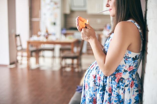 Side view of pregnant mother smoking at home