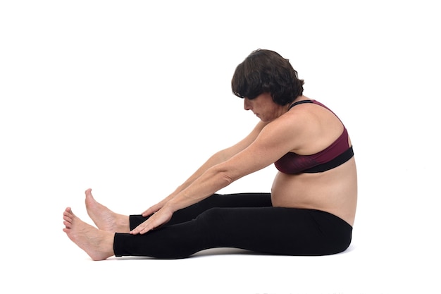 Side view of a pregnant woman doing floor exercises on white background