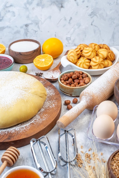 Side view of raw pastry on round board and set of various foods grater on ice background