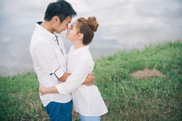 Side view of romantic couple rubbing noses against lake