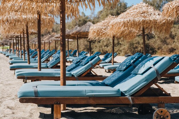 Photo side view of a row of empty blue sun beds under parasols on a beach in mykonos greece