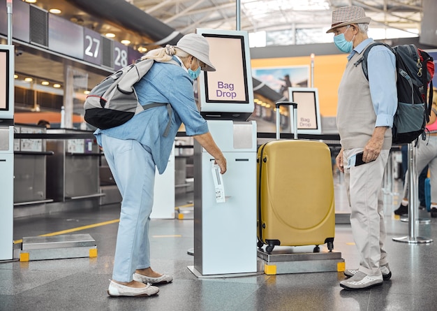 Side view of a senior lady printing out a luggage ticket at the self-service kiosk