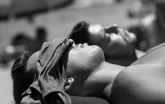 Side view of shirtless man sunbathing at beach during summer