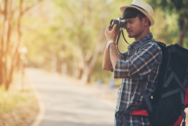 ฺSide view shot of Backpacker photographer photographing outdoors