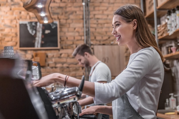 Side view shot of female barista making a cup of coffee