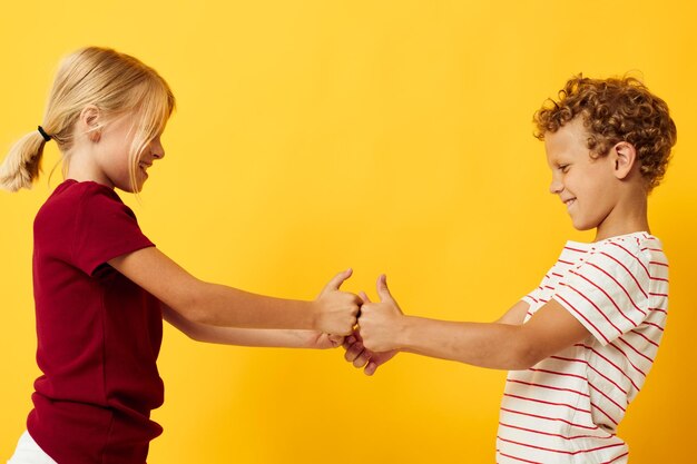 Photo side view of sibling playing against yellow background