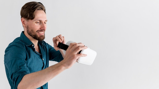 Side view of smiley man holding virtual reality headset with copy space