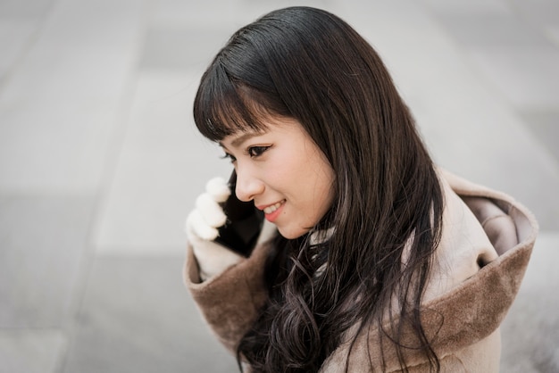 Side view of smiley woman talking on the phone outdoors