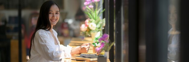 Side view of smiling female university student sitting at wooden counter bar