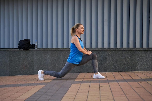 Side view of sportive mature woman in sportswear looking away while warming up outdoors