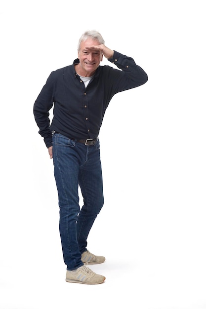 Side view of standing man looking at camera with hand on forehead on white background