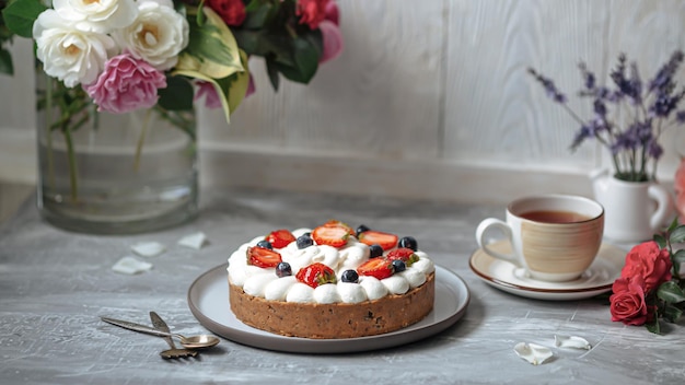 Side view on sweet creamy cake with berries and tea