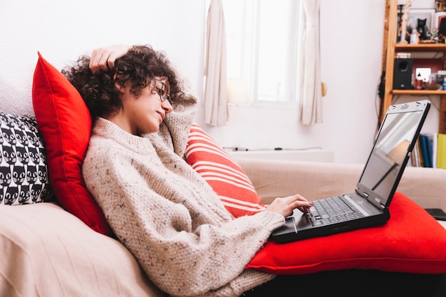 Side view teenager browsing laptop on sofa