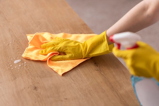 Side view of woman cleaning wooden surface with cloth