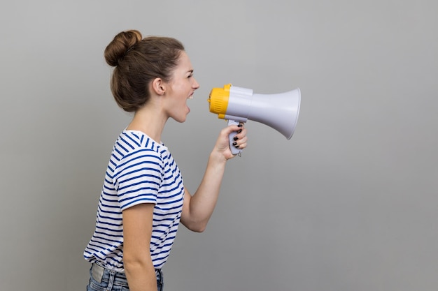 Side view of woman holding megaphone near mouth loudly speaking screaming making announcement