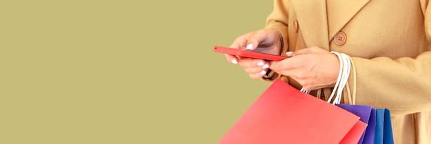 Side view of woman holding smartphone and shopping bags for cyber monday with copy space