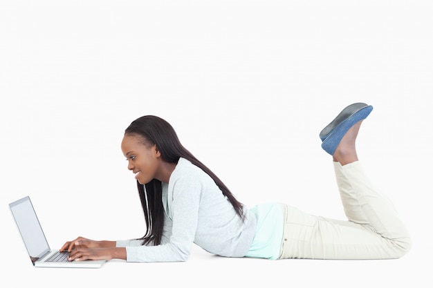 Side view of woman lying on the floor with her laptop