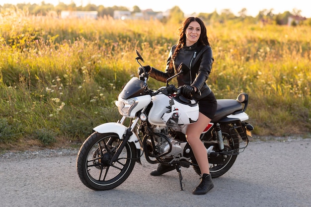 Side view of woman posing while sitting on her motorcycle