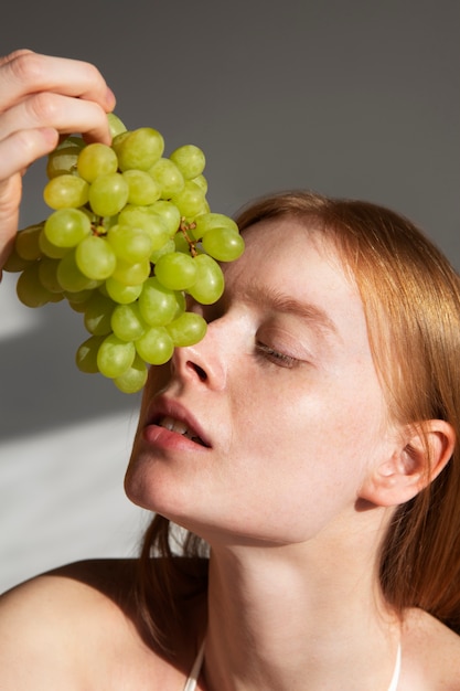 Side view woman posing with green grapes