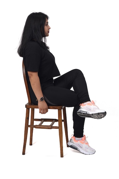 Side view of a woman sitting on a chair with cross legged white background