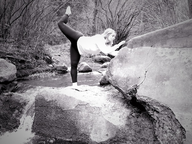 Photo side view of woman standing on rock in forest