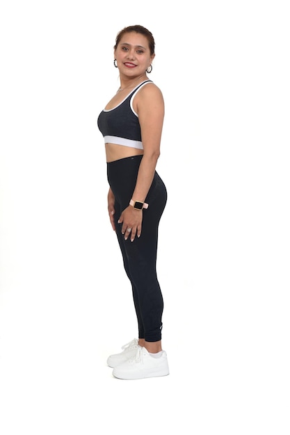 Side view of a woman with sportswear and sneaker looking at camera on white background