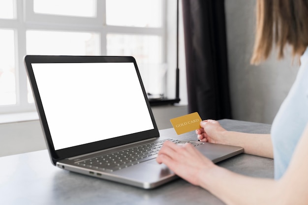 Side view of woman working on laptop and holding credit card