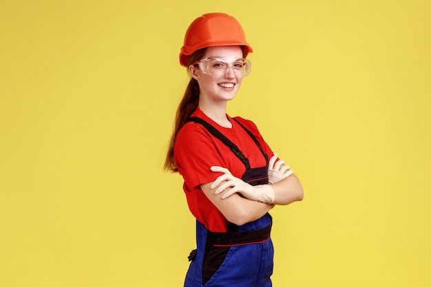 Side view of worker woman standing with crossed arms and looking at camera with confident