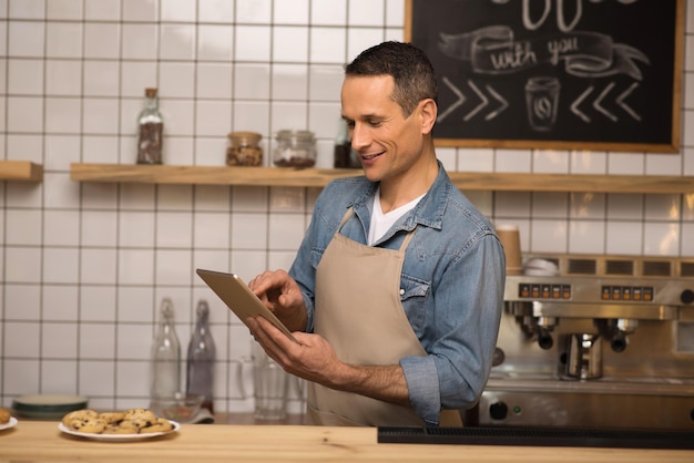 Side view of young waiter using digital tablet in cafe