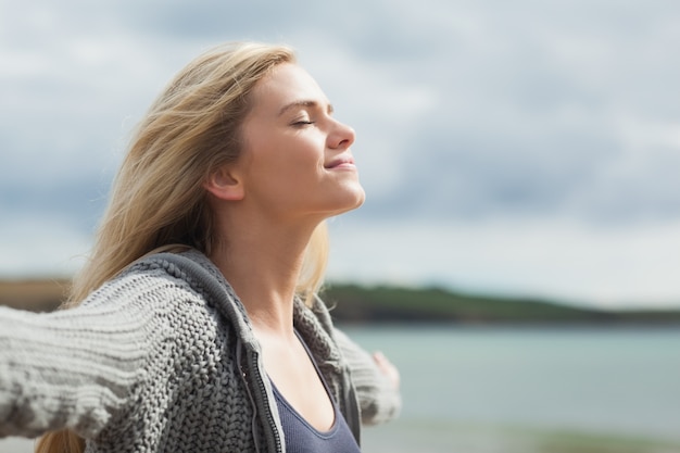 Side view of young woman stretching her arms on beach