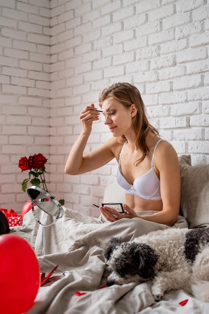 Photo side view of young woman using mobile phone while sitting at home