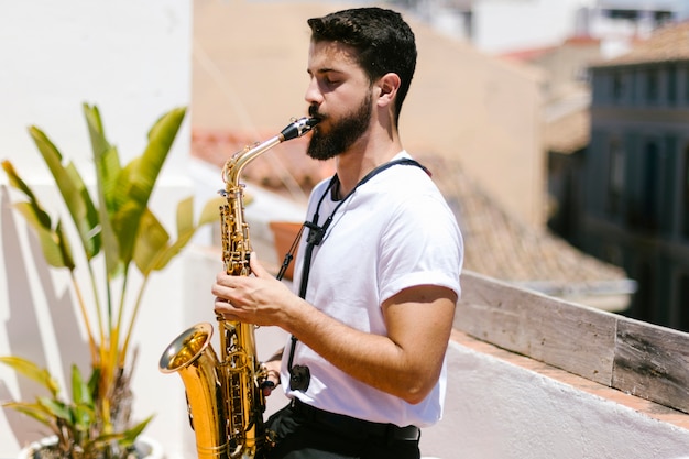 Sideways medium shot of man playing the saxophone 