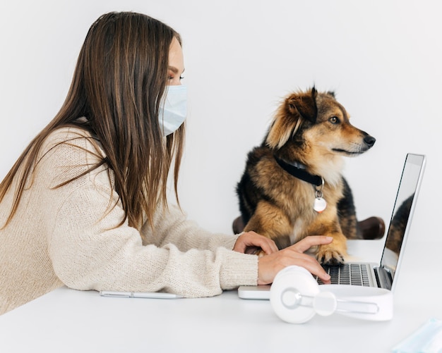 Sideways woman with medical mask playing with her dog