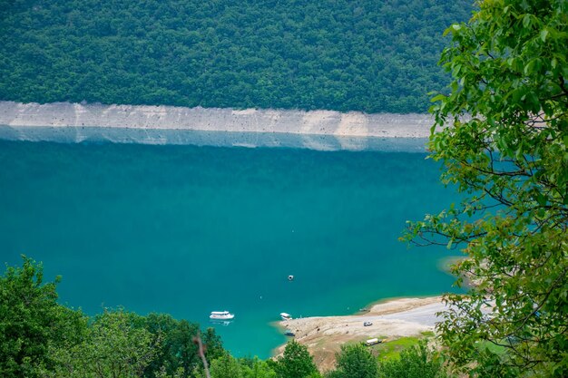 A sightseeing boat with tourists swims along the picturesque lake among the canyon