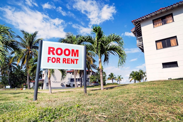 Sign board with text ROOM FOR RENT near modern building in the rural countryside. Rent houses and rooms in a beautiful resort area near the coast