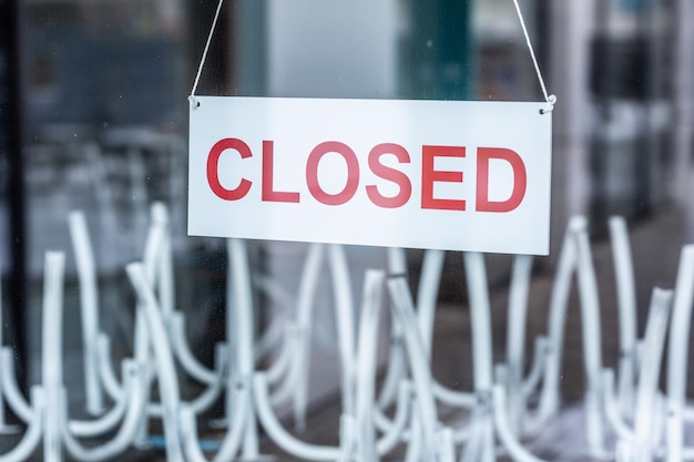 Sign saying closed hanging on the glass door of a restaurant or a bar