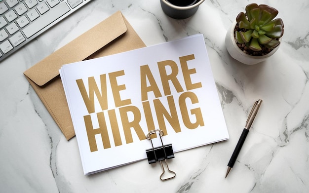 a sign that says we are hiring is on a table