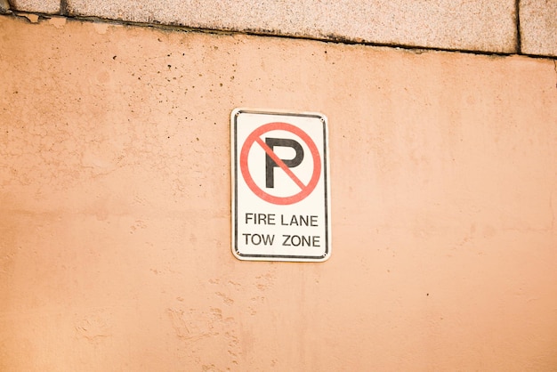 A sign on a wall that says fire lane tow zone.