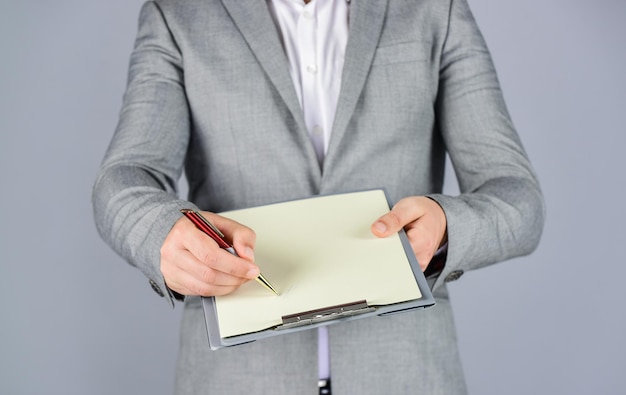 Photo signing the contract pleasant cheerful handsome realtor holding folder bearded man working in office portrait of successful businessman dressed in formal clothes serious boss with document