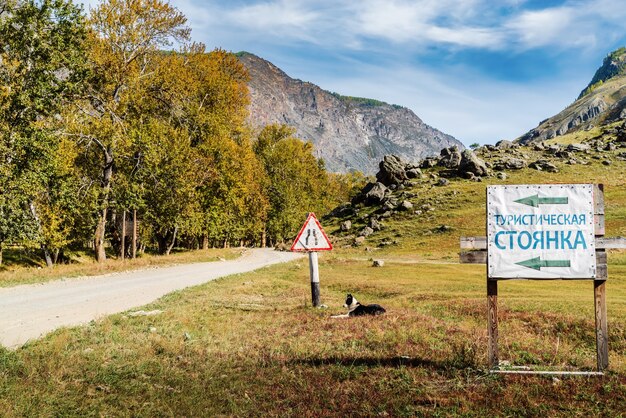 Signpost banner with inscription Tourist parking near dirt road in Chulyshman valley