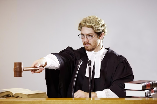 Silence Serious young judge sitting in the courtroom with a stern facial expression while holding out a gavel