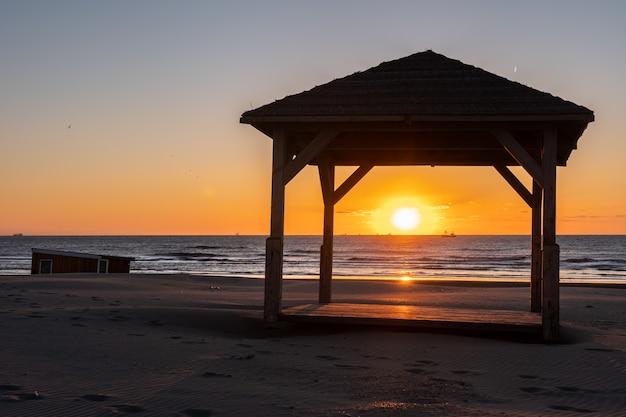 Silhouete of gazebo on the sea beach in beautiful sunset with serene sea in the 