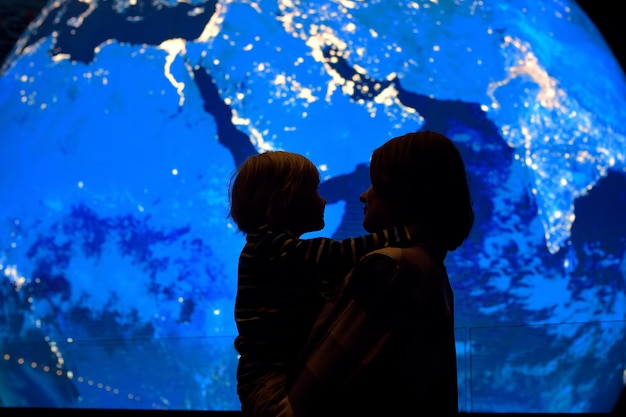 Silhouette of adult and child of globe earth