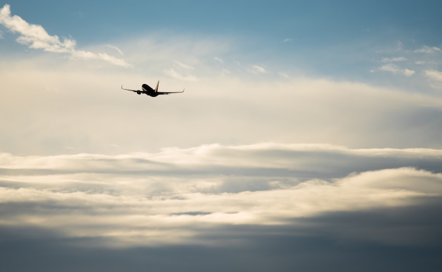 Silhouette airplane flying in the sky surround by blue cloud