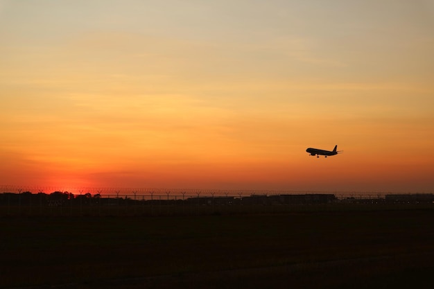 Silhouette of an airplane taking off to the sunset sky