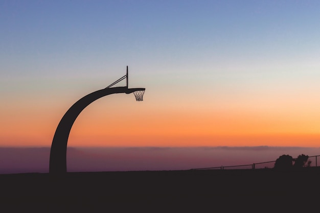 Silhouette of a basketball hoop with the beautiful view of sunset in the background