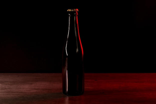 Silhouette of a beer bottle on a black background with red and orange lights