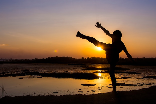 Silhouette of the boys stand and to play with the sunset.