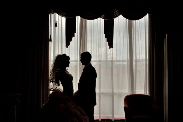 Silhouette of a bride and groom on the background of a window